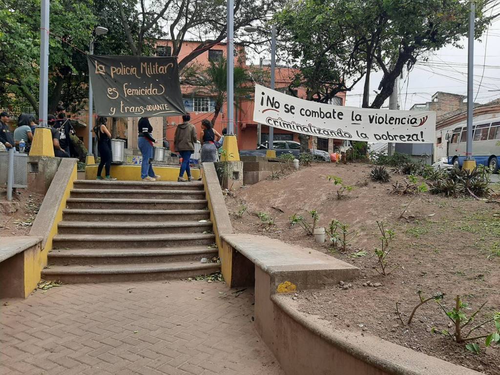 Activistas forman un plantón contra el estado de excepción el 14 de enero 2023 en Parque Finlay, Tegucigalpa, Honduras. Tienen tambores, y sus mantas dicen ¡No se combate la violencia criminalizando la pobreza! y La policia militar es femicida y trans-odiante.