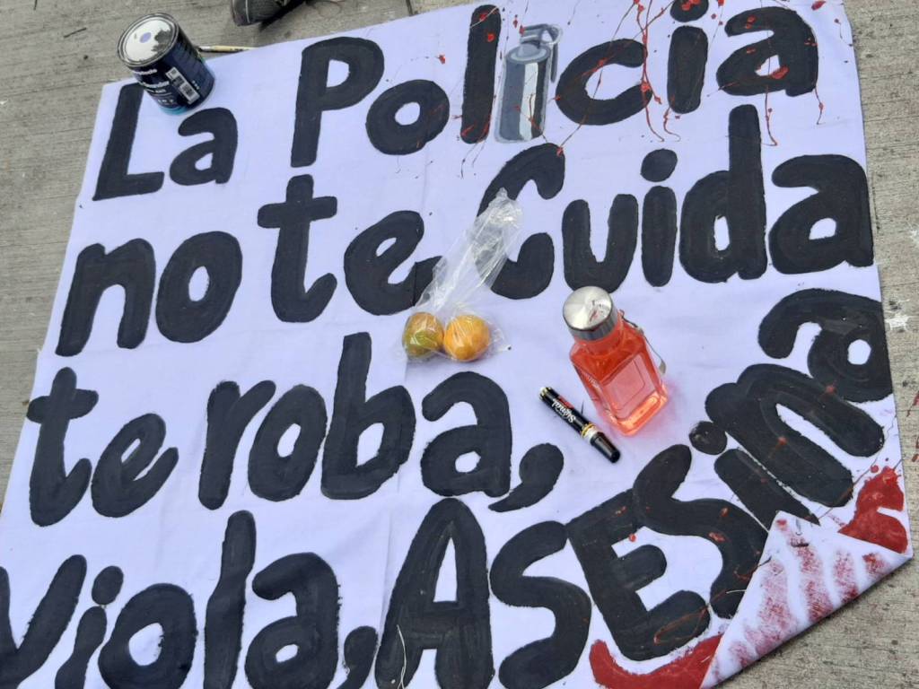 Una manta se seca durante un plantón antimilitarista el 10 de diciembre 2022 en Plaza La Merced, Tegucigalpa, Honduras. La manta dice "la policia no te cuida, te roba, viola, asesina."