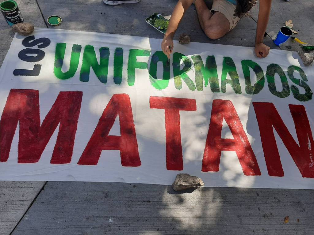 Les activistas antimilitaristas pintan una manta diciendo "los uniformados matan" el 10 de diciembre 2022 en Plaza la Merced, Tegucigalpa, Honduras. 